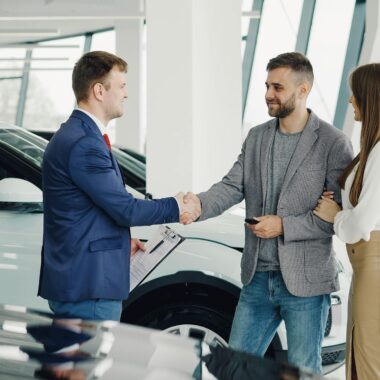 A couple completes a transaction with a salesman at a modern car dealership.